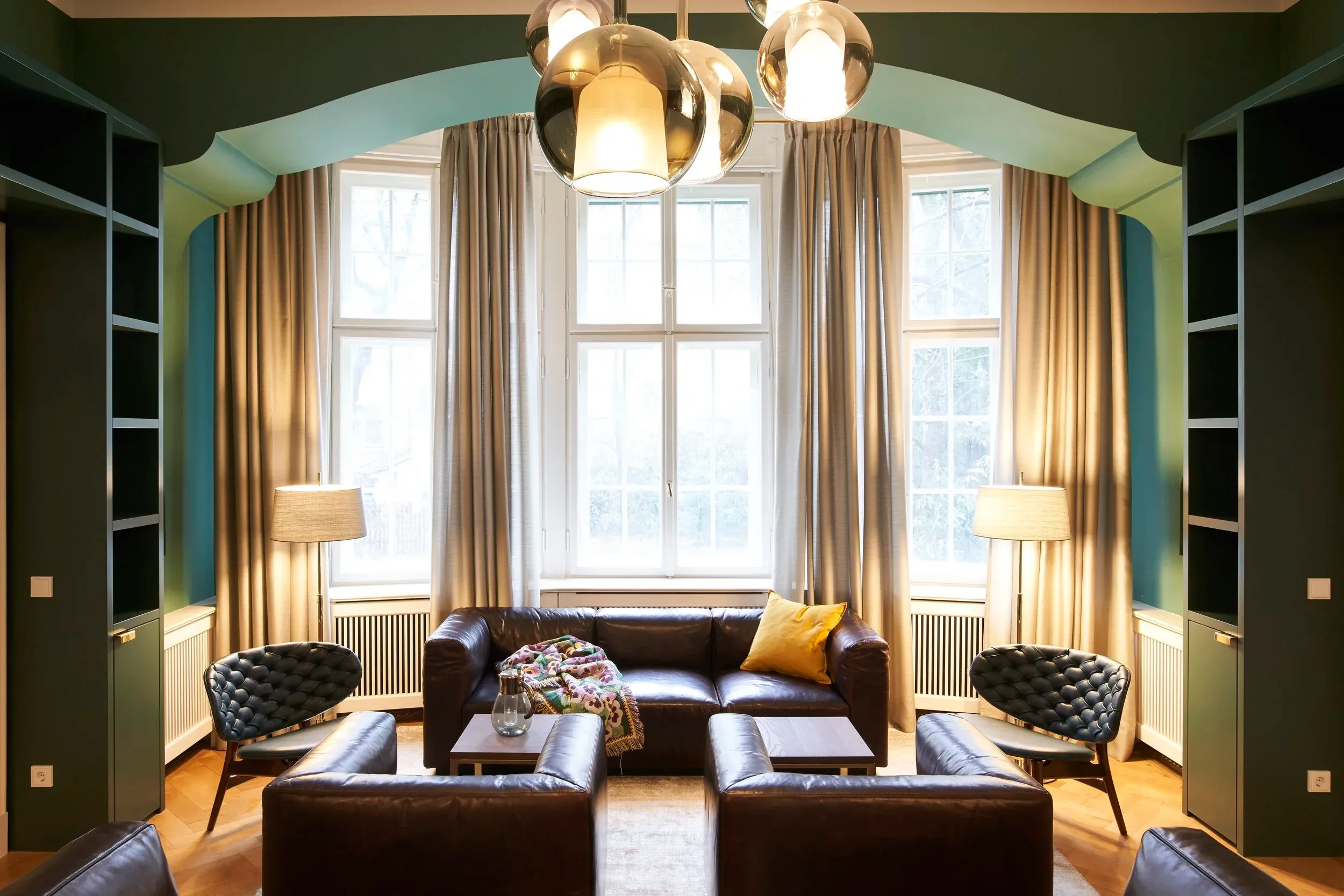 Sitzgruppe mit Ledersofas unter goldenen Kugelleuchten