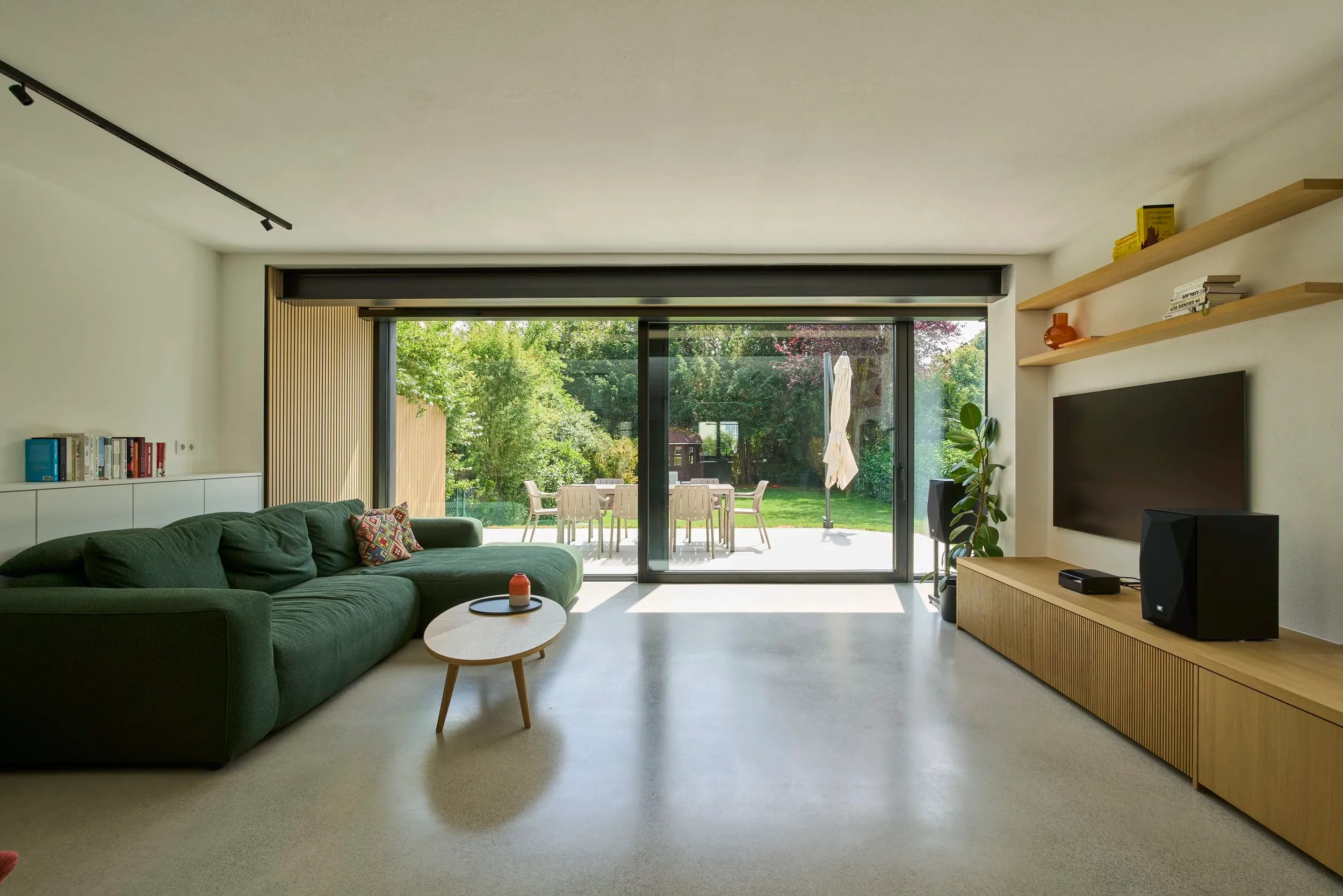 Wohnzimmer mit Sofa und offener Terrassenfront zum Garten