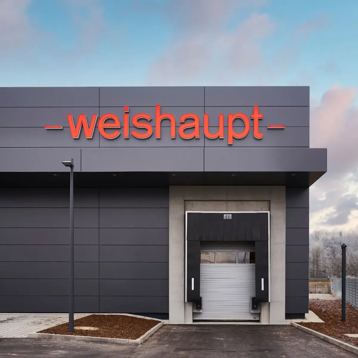 Dunkle Hallenfassade mit rotem Weishaupt-Schriftzug und Verladetor