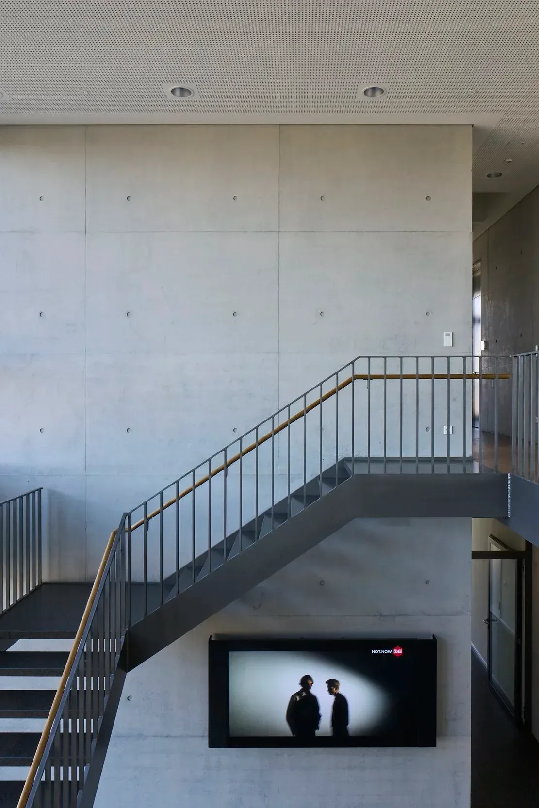 Galerie im Obergeschoss mit Blick auf Treppe und Sichtbetonwand