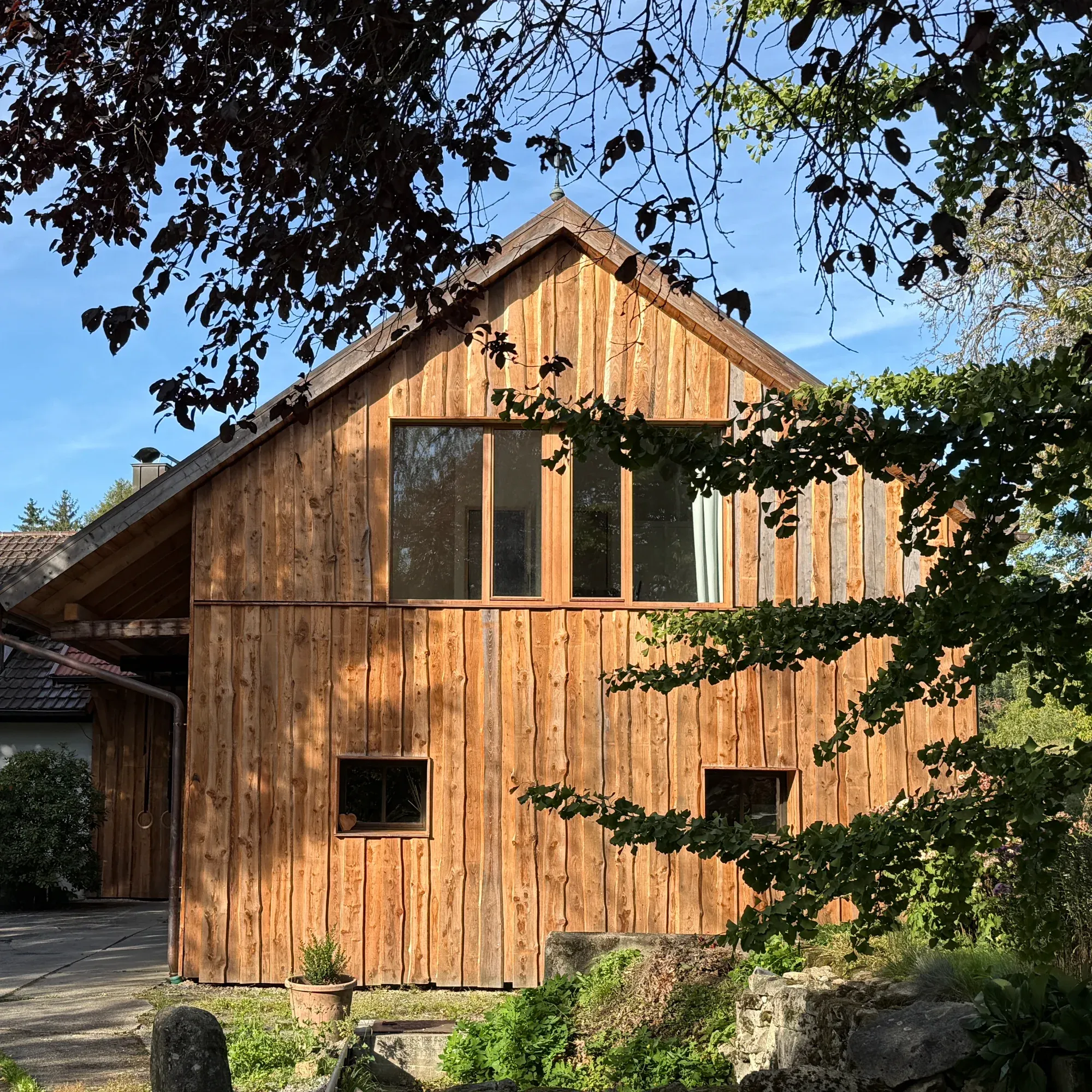 Holzverkleidete Giebelfassade der umgebauten Scheune mit Fenstern