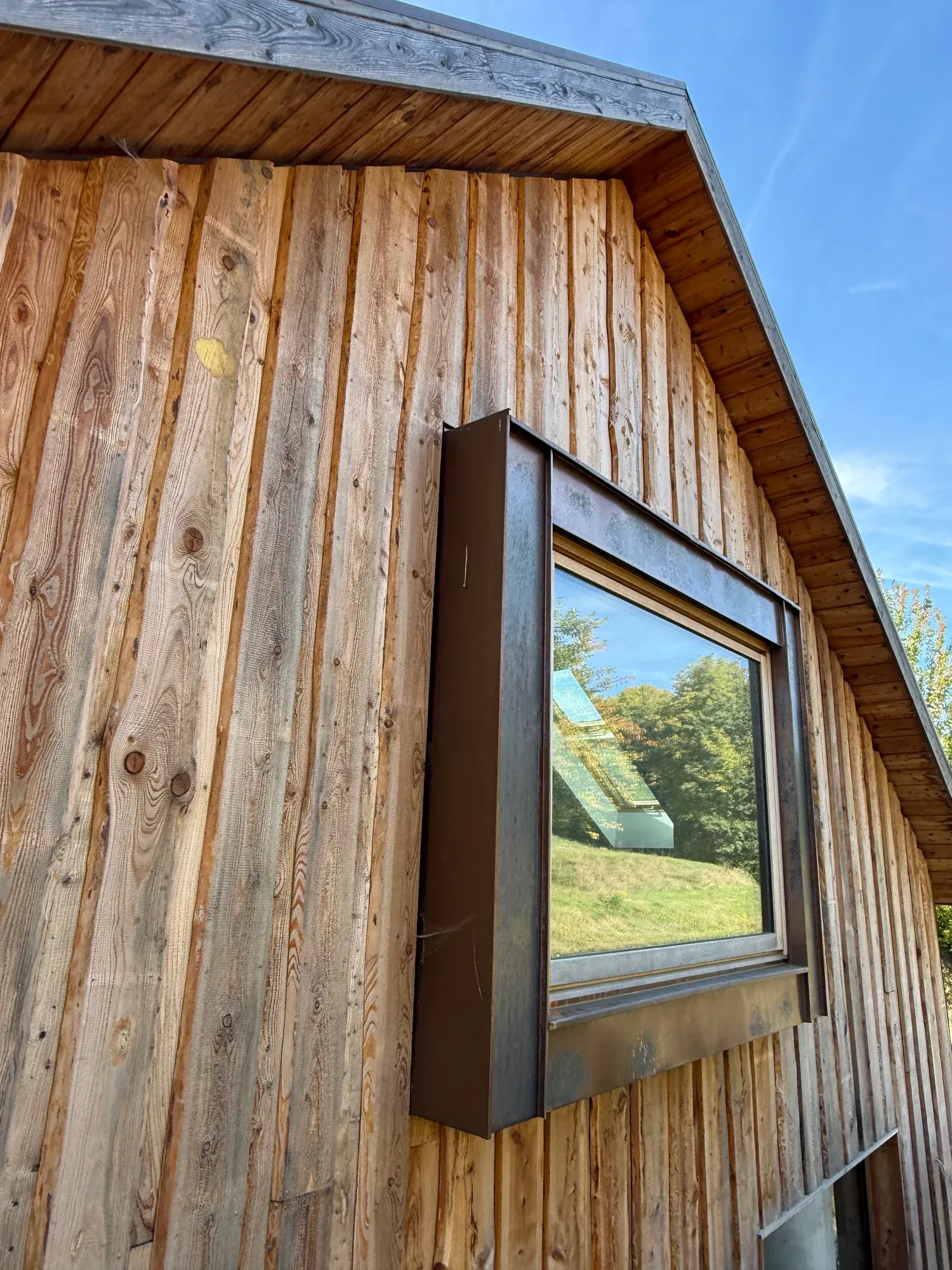 Detail der Holzfassade mit gerahmtem Fenster und Dachüberstand