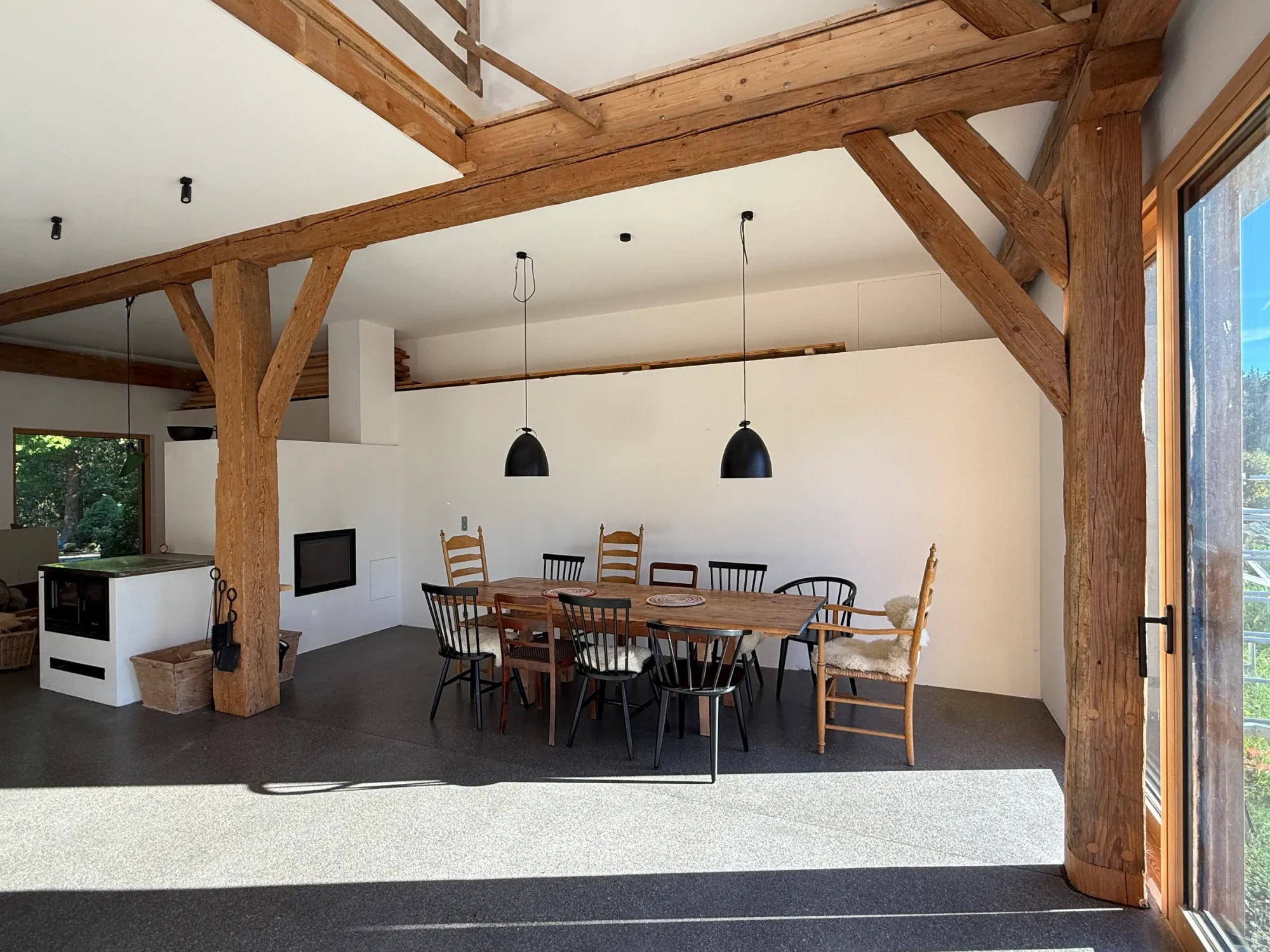 Essbereich mit Holztisch, Ofen und freigelegtem Tragwerk