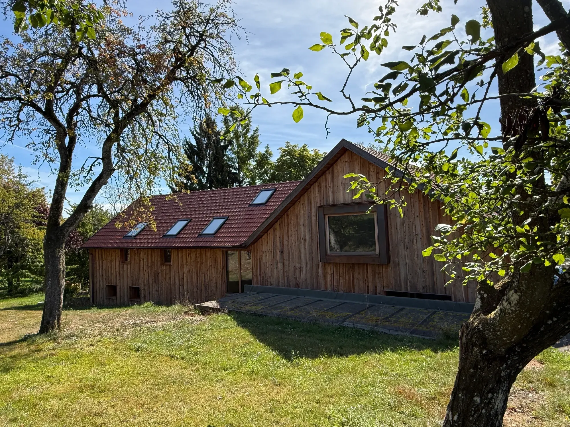 Umgebaute Scheune mit neuer Holzfassade und Giebelfenster am Hang