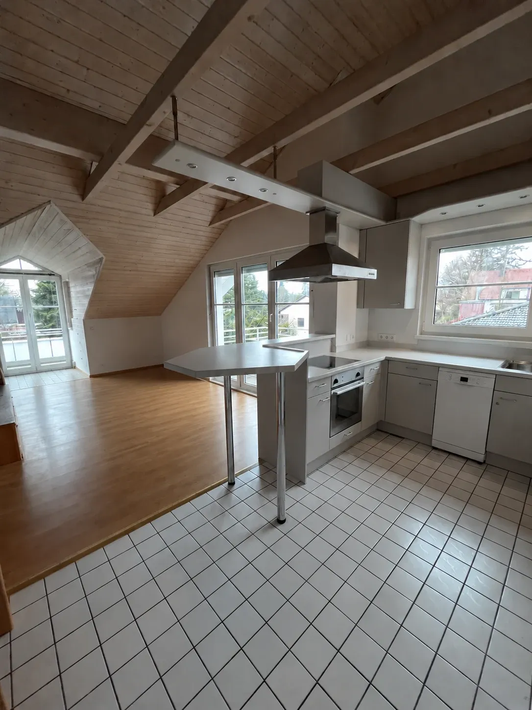 Wohnraum vor der Sanierung mit Holzdecke, sichtbaren Balken und bestehender Küche auf Fliesenboden
